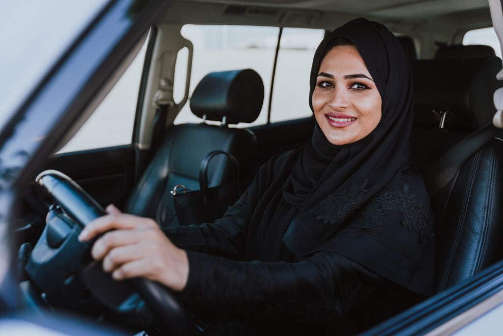 Beautiful woman in Dubai wearing abaya traditional female dress driving the car. Concept about uae and women rights